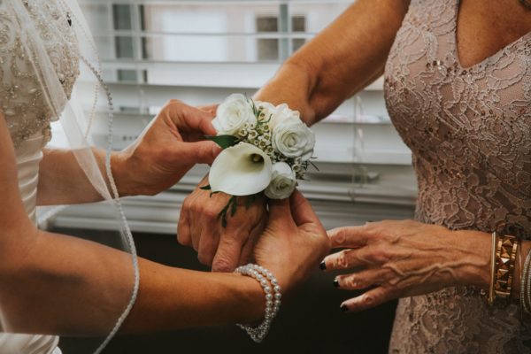 Bride places corsage on mother's w