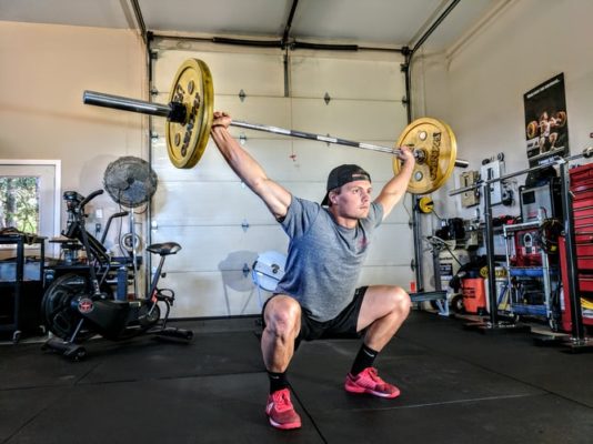 Young man works out with weights from his garage home gym